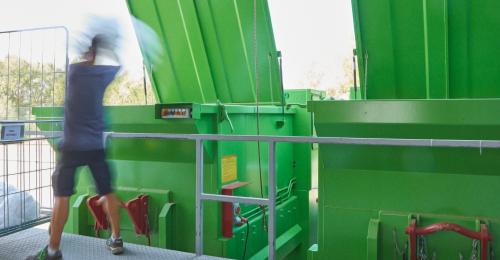 A man by large green bins.