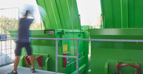 A man by large green bins.