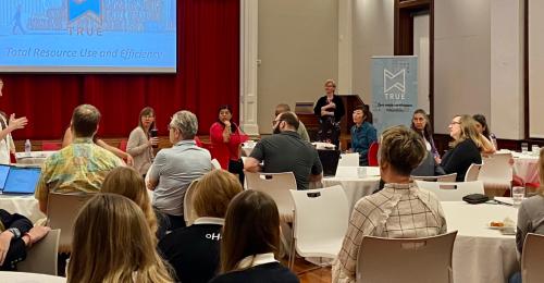 A crowd of people at tables in a TRUE presentation