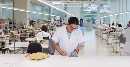 A woman at a lab table in a large facility.