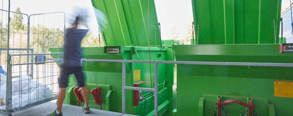 A man by large green bins.