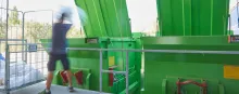 A man by large green bins.