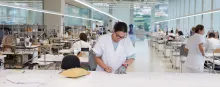 A woman at a lab table in a large facility.